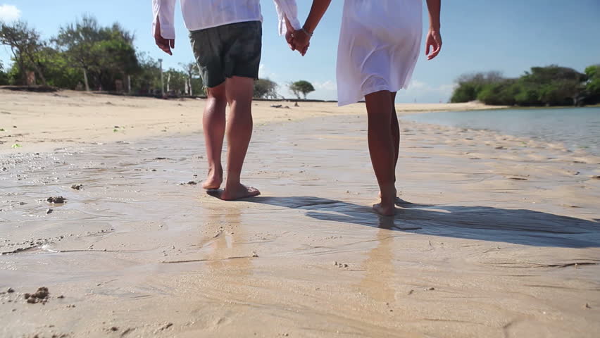Couple feet walking on sand while tropical vacation Bali