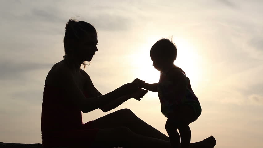 Silhouette of woman haves game with kid over sunlight