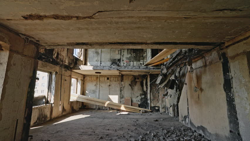War-damaged apartment in Mariupol, reveals collapsed ceilings, burnt interior. Scene of destruction in residential area, exposed urban decay. No people, desolate aftermath visible.