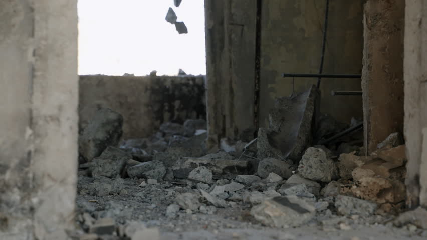 War-damaged building interior shows crumbling concrete, metal rods in Mariupol. Slow motion reveals severe destruction from fire, shelling in residential apartment. Ruins emphasize urban decay. Slowmo