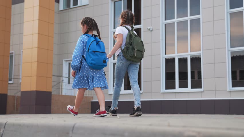 Happy family concept. students hold hands on way to school. happy children with backpacks go to school in first grade. children go to primary school together with backpacks. students go to first grade