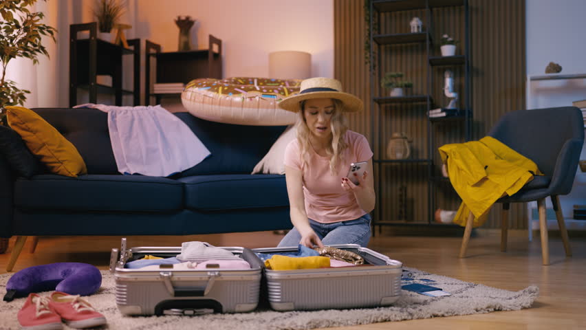 Pleased female uses a packing checklist on her phone to organize for a trip