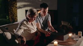 A grandmother and her grandson work together to wrap a gift, creating a warm and collaborative moment in a cozy living room. High quality 4k footage - Powered by Shutterstock - Get 15% off with code: PIKWIZARD15
