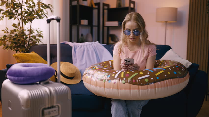 Woman in sunglasses buys cheap flight tickets on her phone, excited to travel