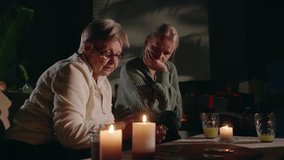A mother and her elderly mother sit by candlelight in a cozy living room as the elderly woman reads tarot cards for her daughter, sharing a meaningful and mystical experience. High quality 4k footage - Powered by Shutterstock - Get 15% off with code: PIKWIZARD15