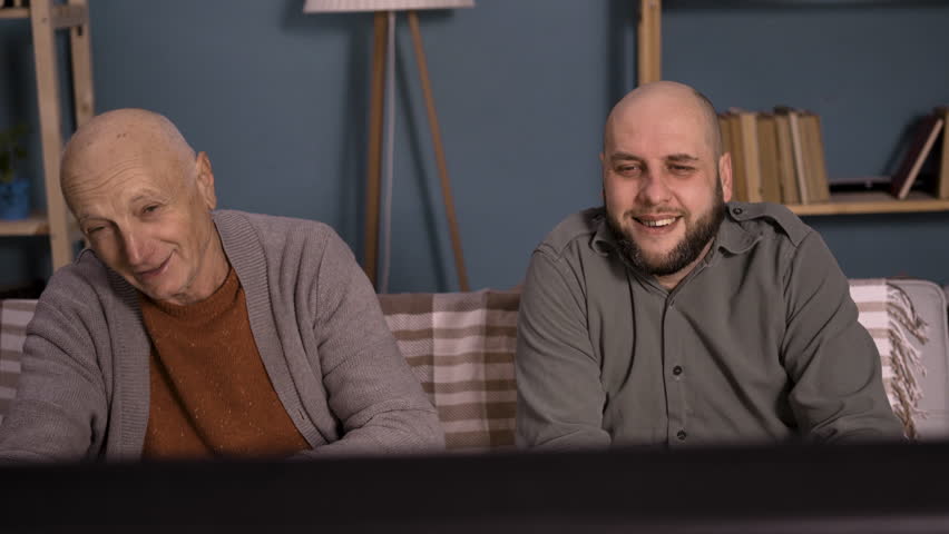 Father and son laughing while watching television together