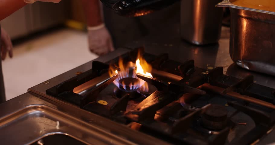 Professional chef flips golden omelette over sizzling gas stove flame. Culinarian prepares healthy meal for lunch using cooking technique slow motion