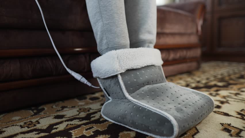 Man warming feet in electric foot warmer.