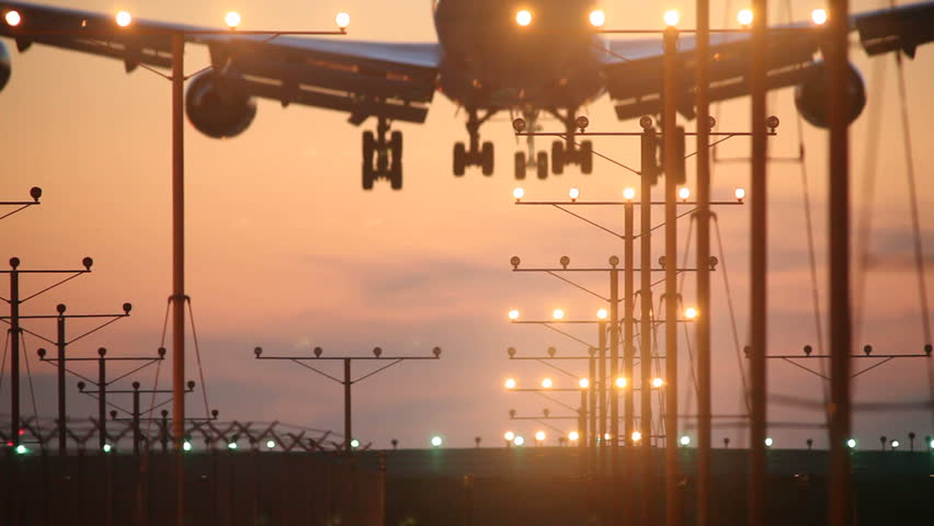 Big airplane plane landing in airport at sunset