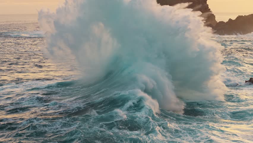 Huge power ocean wave crashing over sunset sky background. Slow motion of stormy ocean surf splashing on the coast of Madeira, Porto Moniz