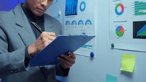 Businessman examines data charts and graphs, meticulously recording observations on a clipboard - Powered by Shutterstock - Get 15% off with code: PIKWIZARD15