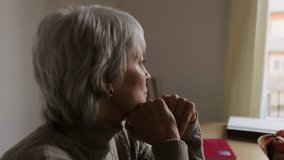 An elderly woman with gray hair sits alone at her table, lost in thought, possibly dealing with loneliness or depression. - Powered by Shutterstock - Get 15% off with code: PIKWIZARD15