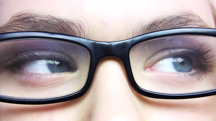 Eyes of a young woman in black glasses read three lines of text (eyes move