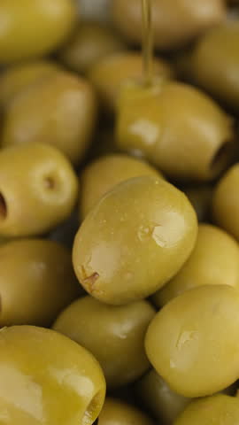 Pouring olive oil on green olives
