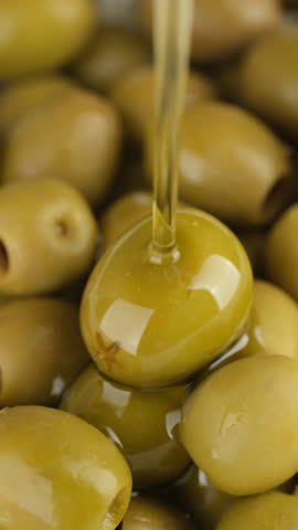 Pouring olive oil on green olives
