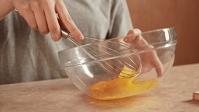 Woman sitting at the table at home in the kitchen and preparing dough for waffles breakfast, breaking egg in the bowl and whisking it. Slow motion. - Powered by Shutterstock - Get 15% off with code: PIKWIZARD15