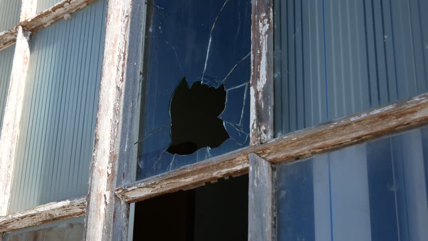 Broken window in an old wooden shabby frame. Hole in the glass. Old-fashioned window. Vandalism.