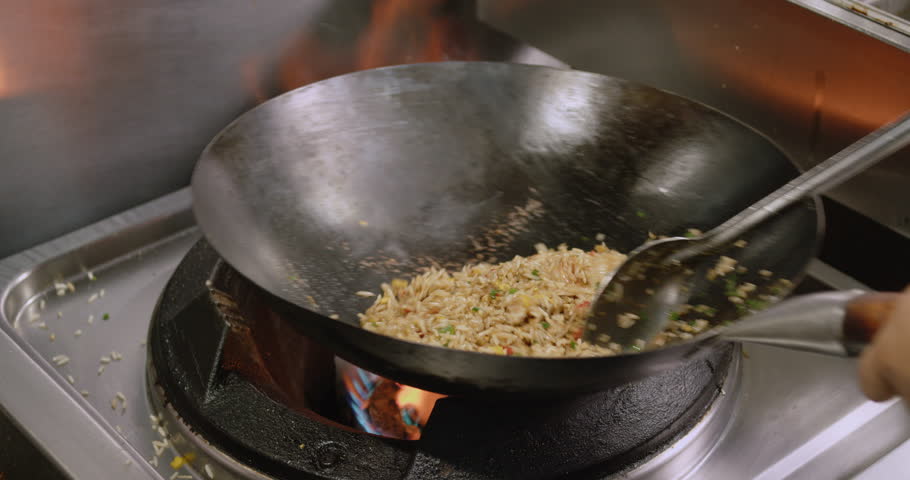 A Close-up of a chef cooking Peruvian shrimp fried rice in a big pan