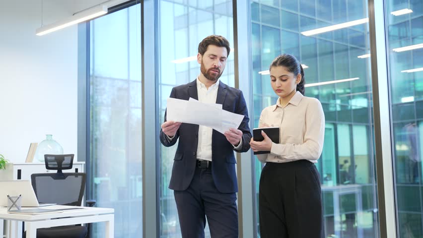 Professional business meeting between two financiers in modern office, discussing important documents with focus collaboration on work project. Colleagues consult about details, busy with paperwork - Powered by Shutterstock - Get 15% off with code: PIKWIZARD15