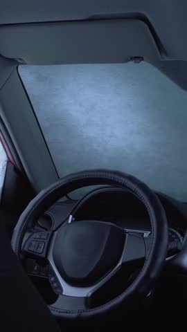 Driver uses brush to clean snow off car. Frozen storm. Brushing parked transport. Winter weather, blizzard season. Vehicle care