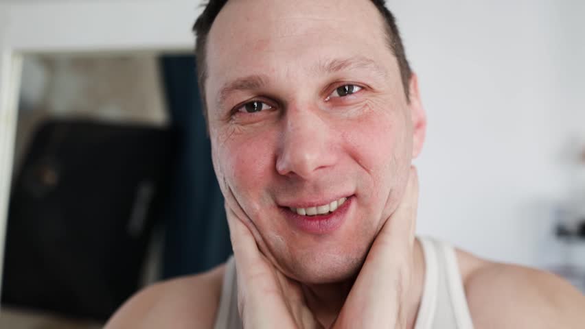 Close up of a man with moisturizer for his face smiling because he hydrates his skin and protects against impurities with anti-aging effects. Concept of: beauty and body care, creams, skincare.