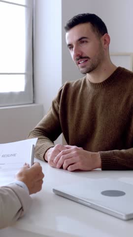 Vertical HD video of young man doing a job interview with senior female recruiter. Employment and labor concept.