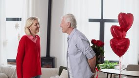 old man senior giving flowers and heart-shaped balloons to his wife kissing, hugging and congratulating at home, elderly couple celebrating Valentine's Day and making romantic date - Powered by Shutterstock - Get 15% off with code: PIKWIZARD15