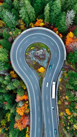 Aerial drone view winding mountain road between autumn trees. Vehicles driving through the curve. Serpentine road Black Forest southern Germany. High quality 4k footage