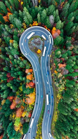 Aerial drone view winding mountain road between autumn trees. Vehicles driving through the curve. Serpentine road Black Forest southern Germany. High quality 4k footage