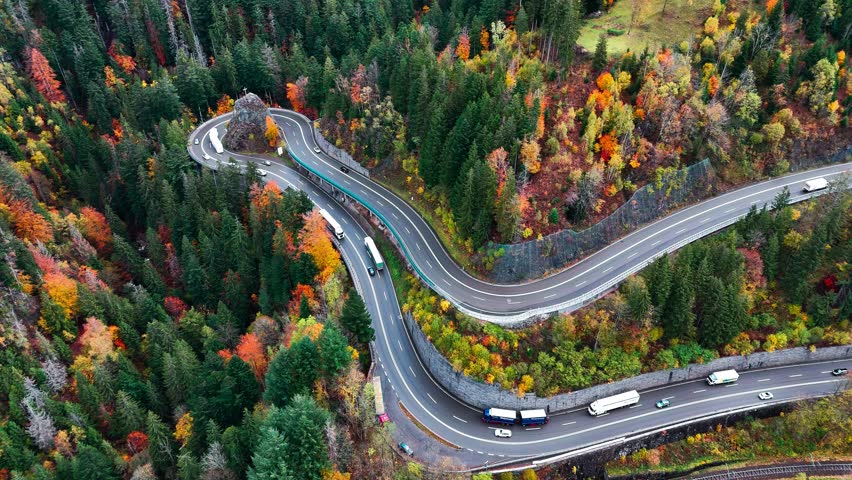 Aerial drone view winding mountain road between autumn trees. Vehicles driving through the curve. Serpentine road Black Forest southern Germany. High quality 4k footage