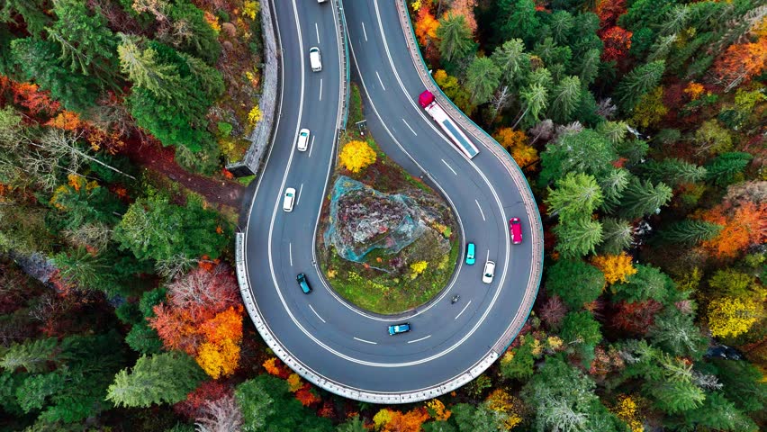 Aerial drone view winding mountain road between autumn trees. Vehicles driving through the curve. Serpentine road Black Forest southern Germany. High quality 4k footage