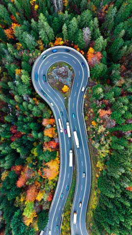 Aerial drone view winding mountain road between autumn trees. Vehicles driving through the curve. Serpentine road Black Forest southern Germany. High quality 4k footage