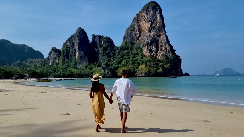 Stroll along the serene sands of Railay Beach Krabi in Thailand, surrounded by majestic limestone cliffs. Feel the warm breeze as waves gently lap against the shore at this idyllic destination.