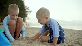 Two young boys are enjoying themselves at the beach as they play in the sand. They are focused on building their creations under the bright sun, with gentle waves in the background. - Powered by Shutterstock - Get 15% off with code: PIKWIZARD15
