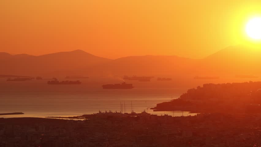 Sunset over Piraeus bay. View from above to industrial cargo ships coming to or departing from Piraeus Port of Athens. Greek cargo transportation by the sea industry. 4k video