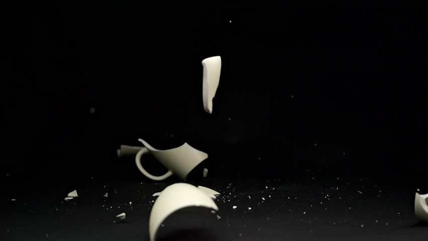 A simple mug crashes to the ground, breaking apart in slow motion as pieces scatter dramatically on a sleek matte black backdrop.