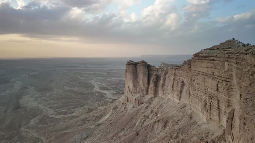 Hyperlapse on dramatic rock formations at Jebel fihrayn near Riyadh, Saudi Arabia, create a breathtaking sunset view over the expansive desert landscape, casting long shadows on rugged terrain