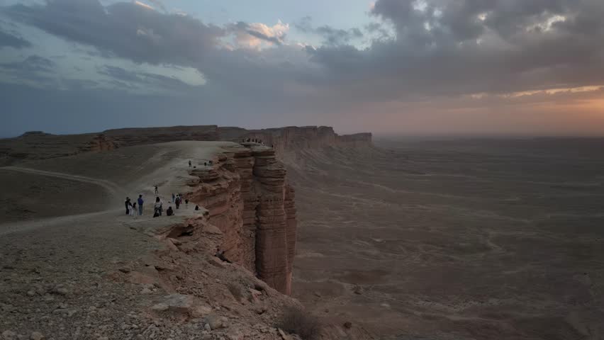 Hyperlapse on dramatic rock formations at Jebel fihrayn near Riyadh, Saudi Arabia, create a breathtaking sunset view over the expansive desert landscape, casting long shadows on rugged terrain