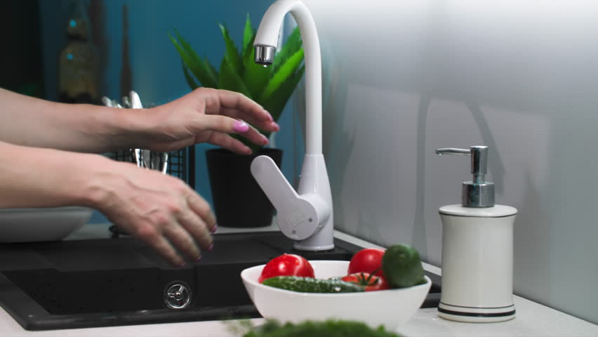 young housewife washing fresh vegetables in sink with water in kitchen, close-up