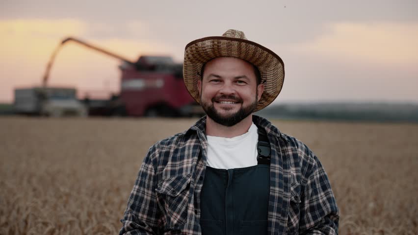 Cheerful agronomist smiling to camera in golden rye field in harvest season. Portrait of successful farmer, agribusiness and agriculture, farming and growing cereals for food, beautiful farmland