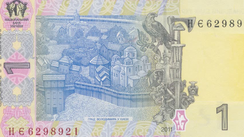 Detailed view of Ukrainian one hryvnia banknote reverse side featuring traditional symbols of power including falcon, sword, mace and cross, showcasing rich historical heritage through intricate ornam