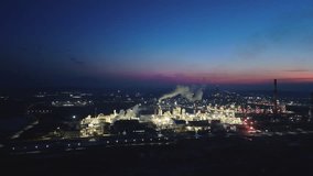 oil refinery is visible against the background of blue sky with pink tint, illuminated by flickering lights.Plumes of smoke rise from the chimneys, emphasizing the activity of the enterprise at night  - Powered by Shutterstock - Get 15% off with code: PIKWIZARD15