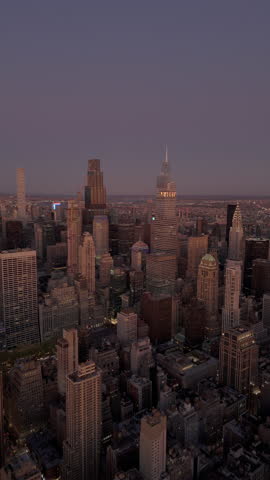 Vertical scenes of the New York City skyline highlight Empire State Building towering among skyscrapers in Midtown Manhattan, lighting up urban landscape with city lights