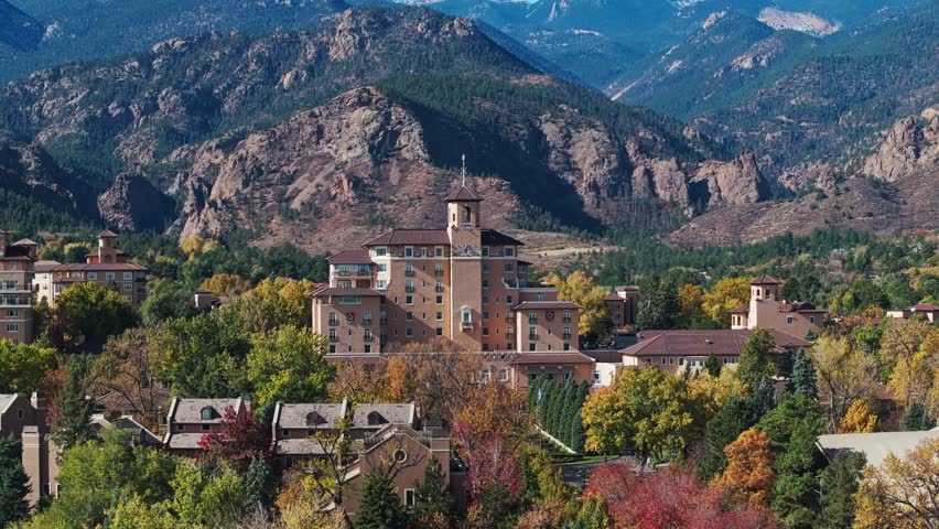 Aerial panoramic of Colorado Springs and The Broadmoor resort in peak fall colors, telephoto compression against mountains