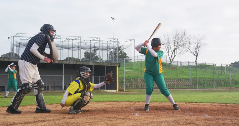 Multiracial female baseball players and male umpire, hitting and throwing the ball on a pitch. sports, activity, teamwork, competition and baseball.