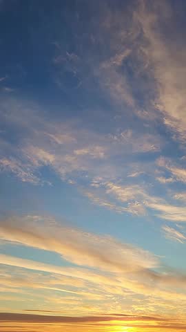 Winter landscape. Panoramic view of beautiful sunset on bay. List clouds over water in bright light. Ice, snow and rocks on coastline. Setting sun is reflected in sea. High quality footage