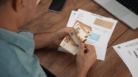 Mature businessman counts stack of euros reading utility bills at office table, male company accountant calculates fifty euro banknotes studying household expenses slow motion - Powered by Shutterstock - Get 15% off with code: PIKWIZARD15