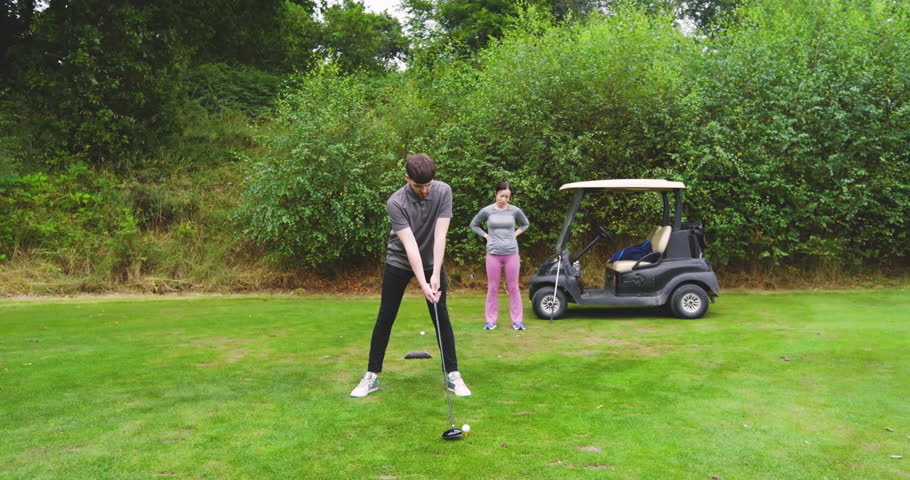 Two male and female golf players playing golf together, hitting the ball with club on a golf course. sports, activity and golf.