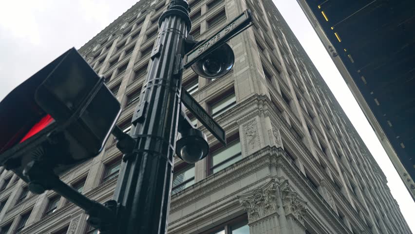 Upward rotating angle around ornate lamp post with street signs and historic building