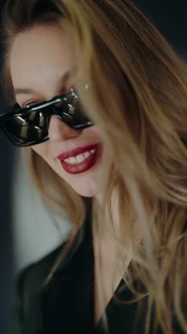 Close-up portrait of a stylish woman wearing sunglasses and red lipstick. The image captures sophistication and fashion with a modern touch. Stylish Woman Wearing Sunglasses with Red Lipstick.Vertical